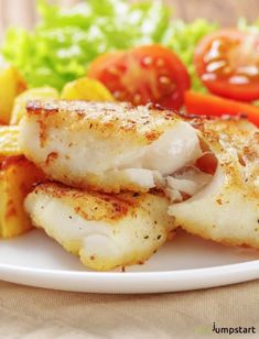 a white plate topped with fish and vegetables