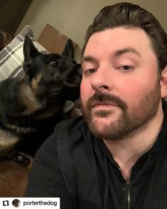 a man sitting on the floor next to a dog and looking up at his face