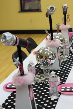 the table is set up with pink and black decorations, silverware, and disco ball centerpieces