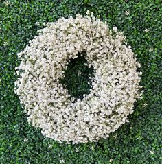 white flowers are arranged in the shape of a wreath on top of green grass and shrubbery