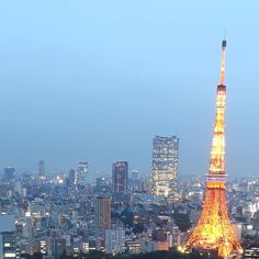 the eiffel tower is lit up at night, with other tall buildings in the background