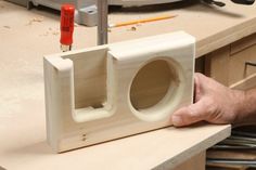 a person holding a wooden object with holes in the front and back, on top of a workbench