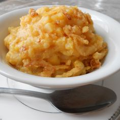 a white bowl filled with mashed potatoes on top of a plate next to a fork