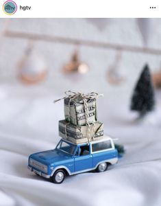 a toy car with stacks of money sitting on top of it's roof in front of a christmas tree