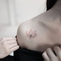 a woman with a flower tattoo on her shoulder is looking at the camera while she adjusts it