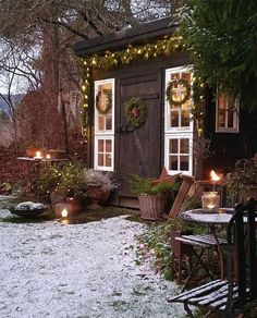 a small cabin with christmas lights and wreaths on the front door is lit up