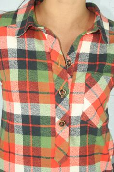 a woman wearing an orange, green and black plaid shirt with buttons on the chest