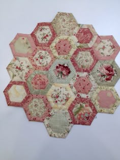 a hexagonal patchwork piece with pink and white flowers on the center is shown