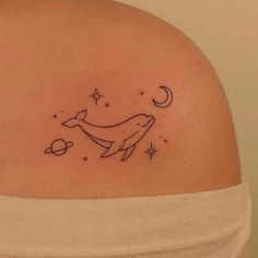 a woman's back shoulder with a tattoo of two dolphins and stars on it