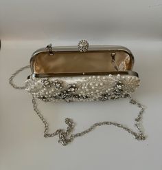 The Pearl Purse is a stylish blend of sophistication and glamour. It is crafted with precision and attention to details. This beaded purse is a must have addition to your accessory collection. It will glamorize your look and is spacious enough to carry all the essentials. The clutch comes with a detachable chain strap so you can carry it as a clutch or a shoulder & crossbody bag. Dimensions: (LxHxW): 7.5 inches x 4.7 inches x 1.97 inches Material: Pearls and Beads, Satin, Rhinestones Features: K Chic Pearl Clutch For Formal Occasions, Luxury Beaded Handheld Evening Bag, Elegant Handheld Beaded Evening Bag, Luxury Pearl Clutch For Formal Occasions, Luxury Handheld Beaded Evening Bag, Luxury Pearl Evening Bag For Party, Elegant Pouch Bags As Fashion Accessory, Elegant Pearl Bags For Formal Occasions, Elegant Pearl Evening Bag For Events