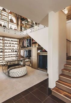 a room with some stairs and lots of shoes on the shelves in it's center