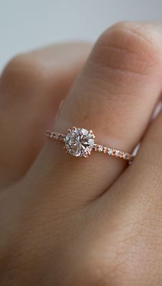 a woman's hand with a diamond ring on top of her finger and an engagement band