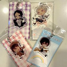 four keychains with anime characters on them sitting next to each other in plastic bags