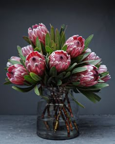 a vase filled with lots of pink flowers on top of a gray countertop next to a wall