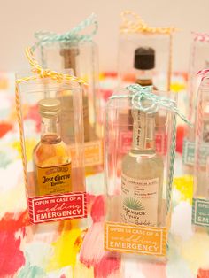 four bottles of perfume sitting on top of a colorful table cloth with tags attached to them