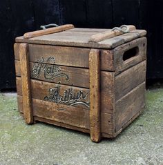 an old wooden box with writing on the lid and handle is sitting in front of a black wall