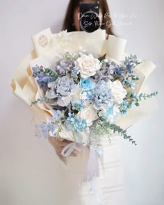 a woman holding a bouquet of blue and white flowers