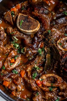 a pot filled with meat and vegetables covered in gravy, garnished with parsley