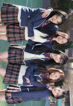 three young women standing next to each other in front of a green grass covered field