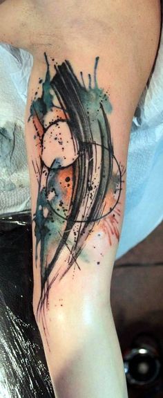 a person with a tattoo on their leg that has watercolor paint splatters all over it