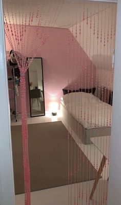 a bedroom with pink curtains hanging from the ceiling and a mirror in the corner behind it