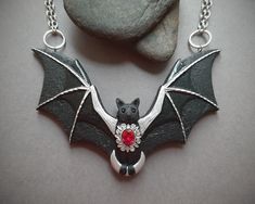 This cute black bat is flying in the sky and carrying the crescent Moon in her paws. The necklace is hand-sculpted of polymer clay and decorated with fancy filigree, glossy enamels and shiny lab created ruby gem. A really statement jewelry piece to make your Halloween or Gothic outfit perfect. Bib width 4 inches. Bib height 2 1/2 inches. Necklace length 20 inches. Please feel free to contact me if you need a customization. Bat Necklace, Bat Jewelry, Elven Jewelry, Halloween Necklace, Polymer Clay Bracelet, Cuff Jewelry, Unusual Earrings, Green Jewelry, Polymer Clay Necklace