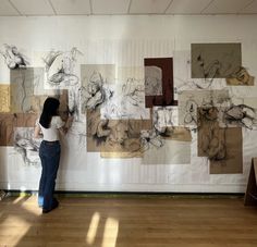 a woman standing next to a wall covered in drawings