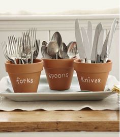 four pots with forks and spoons in them sitting on a plate next to silverware