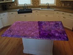 a kitchen with white cabinets and purple marble counter tops in the center of the room