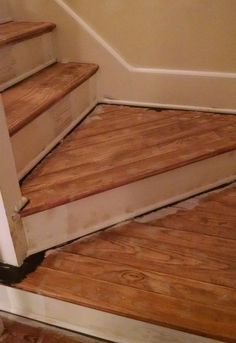 a cat sitting on the floor in front of a stair case next to an open door