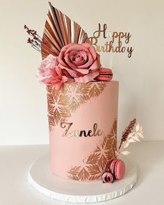 a pink birthday cake decorated with flowers and feathers