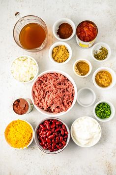 bowls filled with different kinds of food on top of a white countertop next to sauces and condiments