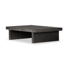 the concrete coffee table is black and has an open end section on one side,