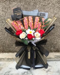 a bouquet of flowers and chocolates in front of a wall