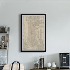 a framed map hangs on the wall above a kitchen counter with dishes and utensils