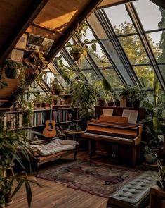 a room filled with lots of plants next to a couch and guitar on top of a wooden floor