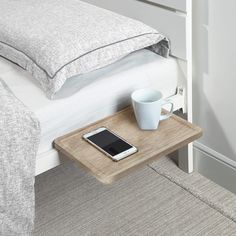 a cell phone sitting on top of a wooden tray next to a cup of coffee