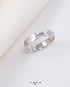 a white gold wedding ring on a plain surface