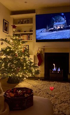 a living room with a christmas tree in front of a tv and fireplace decorated for the holidays