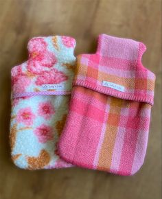 two pink and orange towels sitting next to each other on a wooden table with a tag in the middle