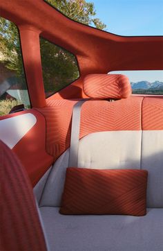 an orange and white car with two pillows on the back seat in front of it