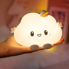 a hand holding a small light with an adorable little cloud on it's face