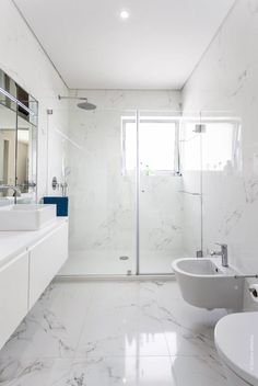 a white bathroom with marble floors and walls