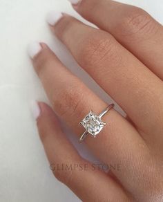 a woman's hand with a diamond ring on top of her finger and the other hand holding it