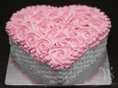 a heart shaped cake with pink frosting roses on it's top and bottom