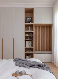 a white bed sitting in a bedroom next to a wooden book shelf filled with books