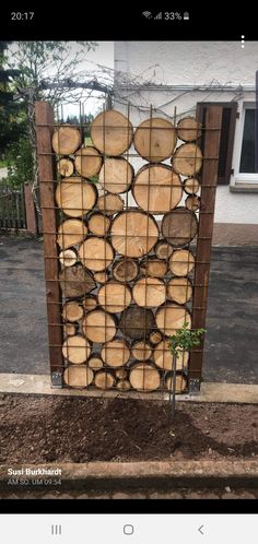 a wooden fence made out of logs in front of a house with a small tree