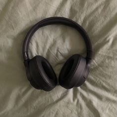 black headphones laying on top of a white sheet