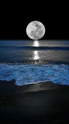 the moon is shining over the ocean with waves coming in to shore and it's reflection on the water