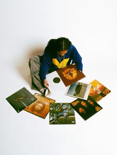 a person sitting on the floor surrounded by pictures and cards with their hands in them